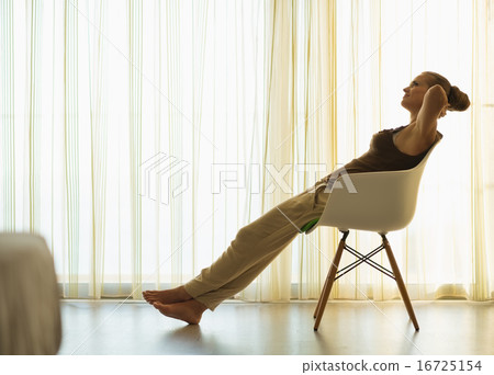 Silhouette of young woman relaxing in modern chair Silhouette of young woman relaxing in modern chair 16725154