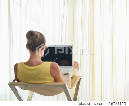 Young woman sitting on modern chair with laptop. rear view Young woman sitting on modern chair with laptop. rear view 16725155