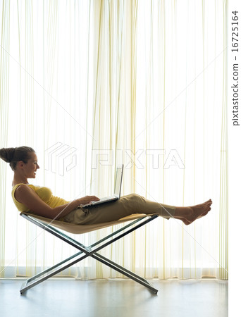 Silhouette of young woman on modern chair and using laptop Silhouette of young woman on modern chair and using laptop 16725164