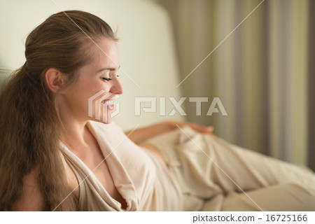 Smiling young woman laying on sofa Smiling young woman laying on sofa 16725166