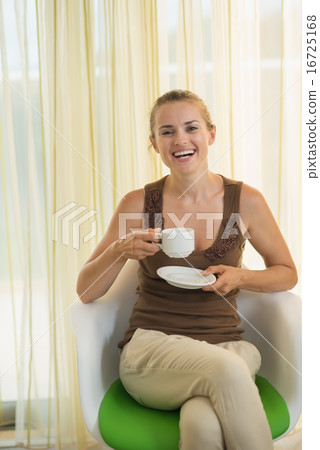 Happy young woman drinking tea in modern chair Happy young woman drinking tea in modern chair 16725168