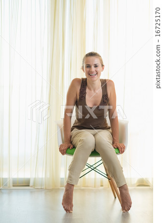 Smiling young woman sitting on modern chair 16725170