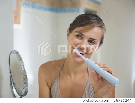 Young woman brushing teeth with electric toothbrush Young woman brushing teeth with electric toothbrush 16725244