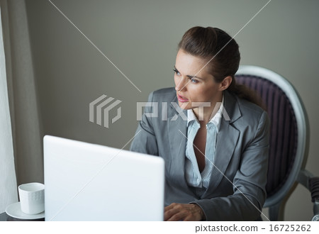Thoughtful business woman in hotel room looking in window 16725262