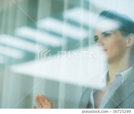 Portrait of business woman looking in window 16725299