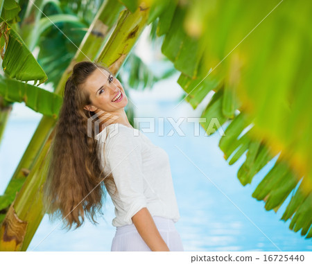 Happy young woman among tropical palms Happy young woman among tropical palms 16725440