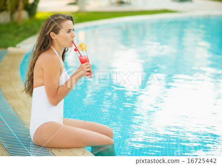 Happy young woman sitting at pool and drinking cocktail Happy young woman sitting at pool and drinking cocktail 16725442