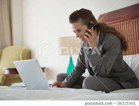 Business woman talking mobile phone and working on laptop in hot 16725501