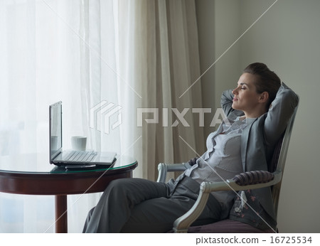 Relaxed business woman sitting in chair in hotel room Relaxed business woman sitting in chair in hotel room 16725534