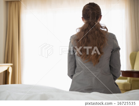 Business woman sitting on bed in hotel room. rear view 16725535