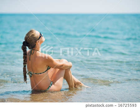 Young woman sitting at seaside . rear view Young woman sitting at seaside . rear view 16725593