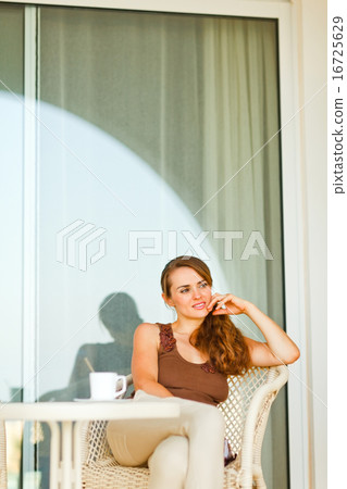 Thoughtful pretty woman with cup of coffee sitting on terrace 16725629