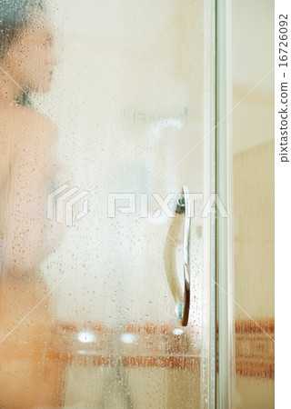 Woman washing behind weeping glass shower door 16726092