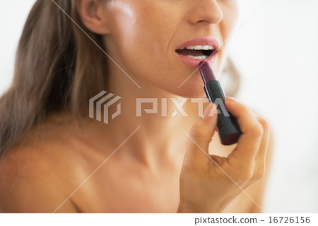 Closeup on woman applying lipstick in bathroom Closeup on woman applying lipstick in bathroom 16726156