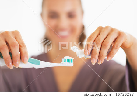 Closeup on happy young woman squeezing toothpaste from tube 16726288