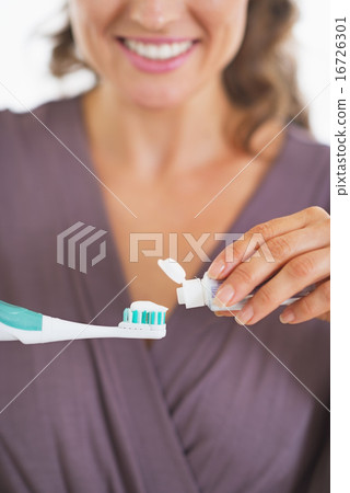 Closeup on young woman squeezing toothpaste from tube Closeup on young woman squeezing toothpaste from tube 16726301