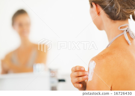 Closeup on young woman applying cream 16726430