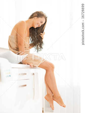 Young woman with long wet hair sitting in bathroom Young woman with long wet hair sitting in bathroom 16726699