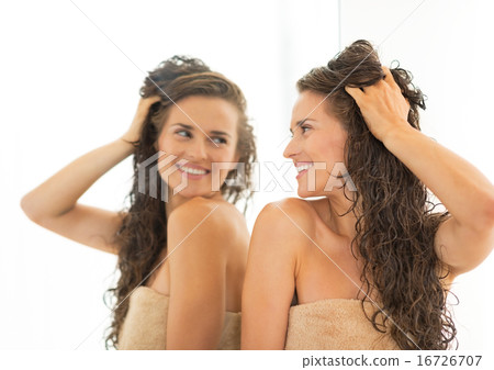 Happy young woman with long wet hair looking in mirror Happy young woman with long wet hair looking in mirror 16726707