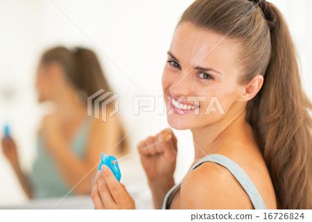 Portrait of happy young woman with dental floss 16726824