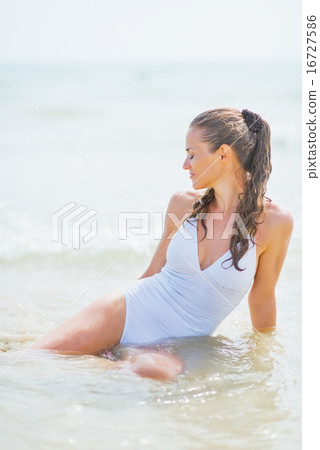 Young woman sitting on sea coast Young woman sitting on sea coast 16727586