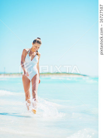 Full length portrait of smiling young woman walking at seaside Full length portrait of smiling young woman walking at seaside 16727587