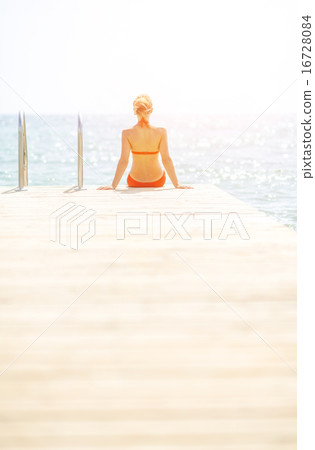 Young woman sitting on bridge. rear view Young woman sitting on bridge. rear view 16728084