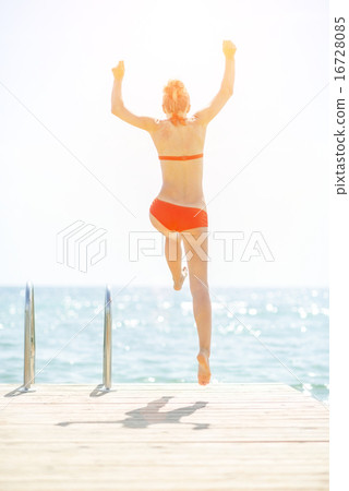 Young woman jumping from bridge into sea. rear view Young woman jumping from bridge into sea. rear view 16728085