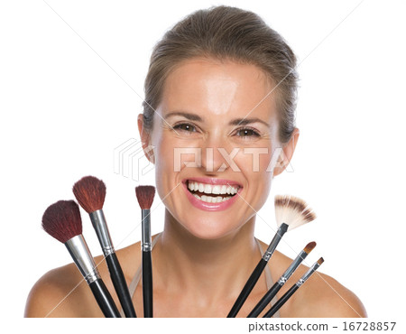 Smiling young woman holding makeup brushes Smiling young woman holding makeup brushes 16728857