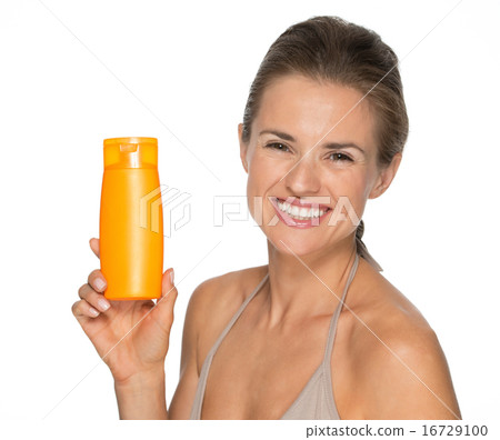 Portrait of happy young woman showing bottle of sun screen creme Portrait of happy young woman showing bottle of sun screen creme 16729100