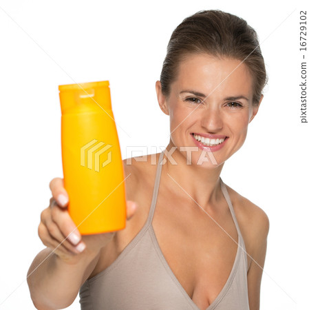 Happy young woman showing sun screen bottle Happy young woman showing sun screen bottle 16729102