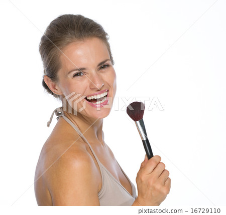 Portrait of smiling young woman with makeup brush Portrait of smiling young woman with makeup brush 16729110