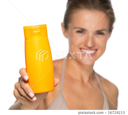 Closeup on happy young woman showing sun screen bottle 16729213