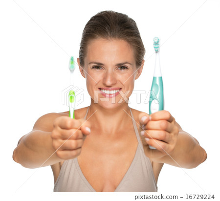 Happy young woman showing old and electric toothbrush Happy young woman showing old and electric toothbrush 16729224