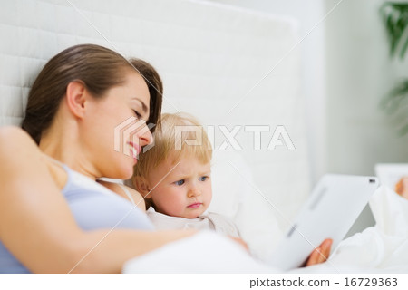 Young mother showing baby something in tablet PC Young mother showing baby something in tablet PC 16729363