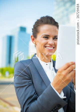 Happy business woman using tablet pc in office district Happy business woman using tablet pc in office district 16729484