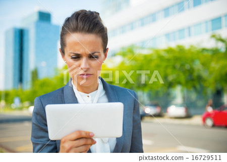 Serious business woman using tablet pc in office district Serious business woman using tablet pc in office district 16729511