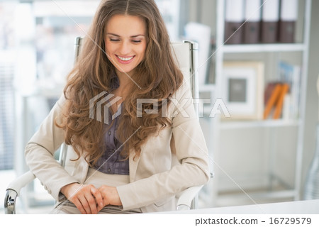 Portrait of happy business woman sitting in office 16729579