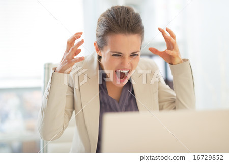 Stressed business woman with laptop at work 16729852