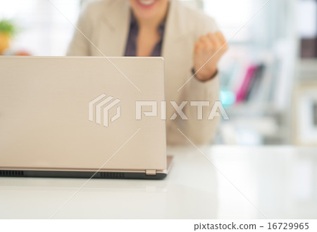 Closeup on laptop and business woman making fist pump in backgro 16729965