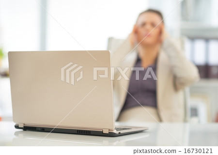 Closeup on laptop on table and stressed business woman in backgr 16730121