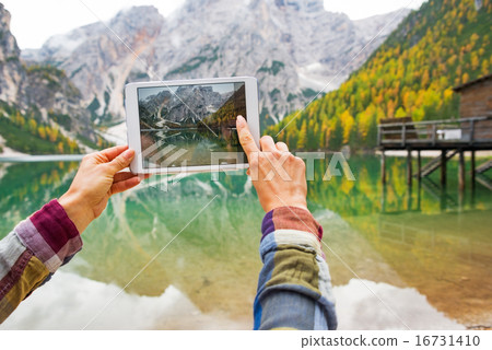 Closeup on young woman taking photo with tablet pc while on lake 16731410