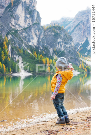 Child throwing stones while on lake braies in south tyrol, italy 16731444