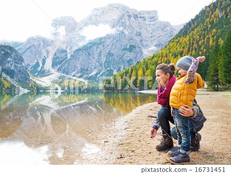 Mother and baby throwing stones on lake braies in south tyrol, i 16731451