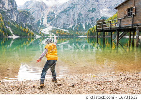 Child throwing stones on lake braies in south tyrol, italy. rear 16731612