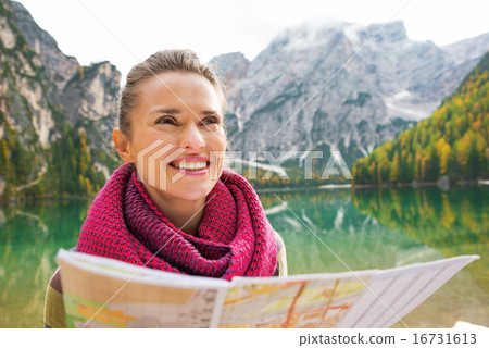 Portrait of happy young woman with map on lake braies in south t 16731613
