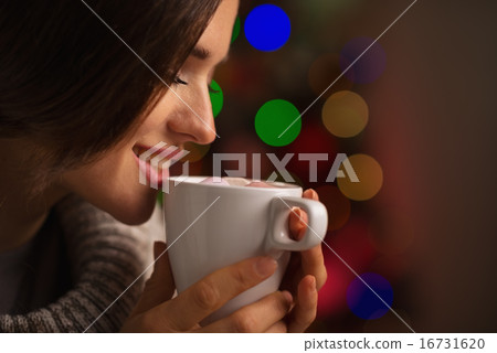 Happy young woman enjoying cup of hot beverage in front of Chris 16731620