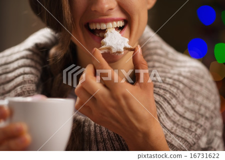 Closeup on happy woman eating Christmas cookie in front of Chris 16731622