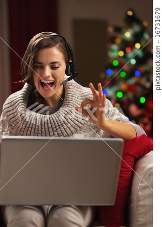 Smiling young woman having video chat with family in front of ch Smiling young woman having video chat with family in front of ch 16731679
