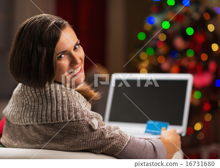 Happy young woman with credit card and laptop in front of Christ Happy young woman with credit card and laptop in front of Christ 16731680